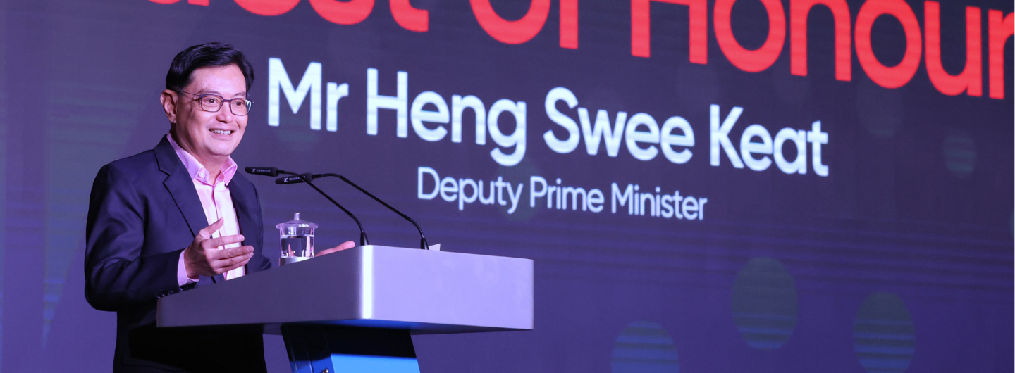 Heng Swee Keat at podium with microphones, name/title text backdrop.